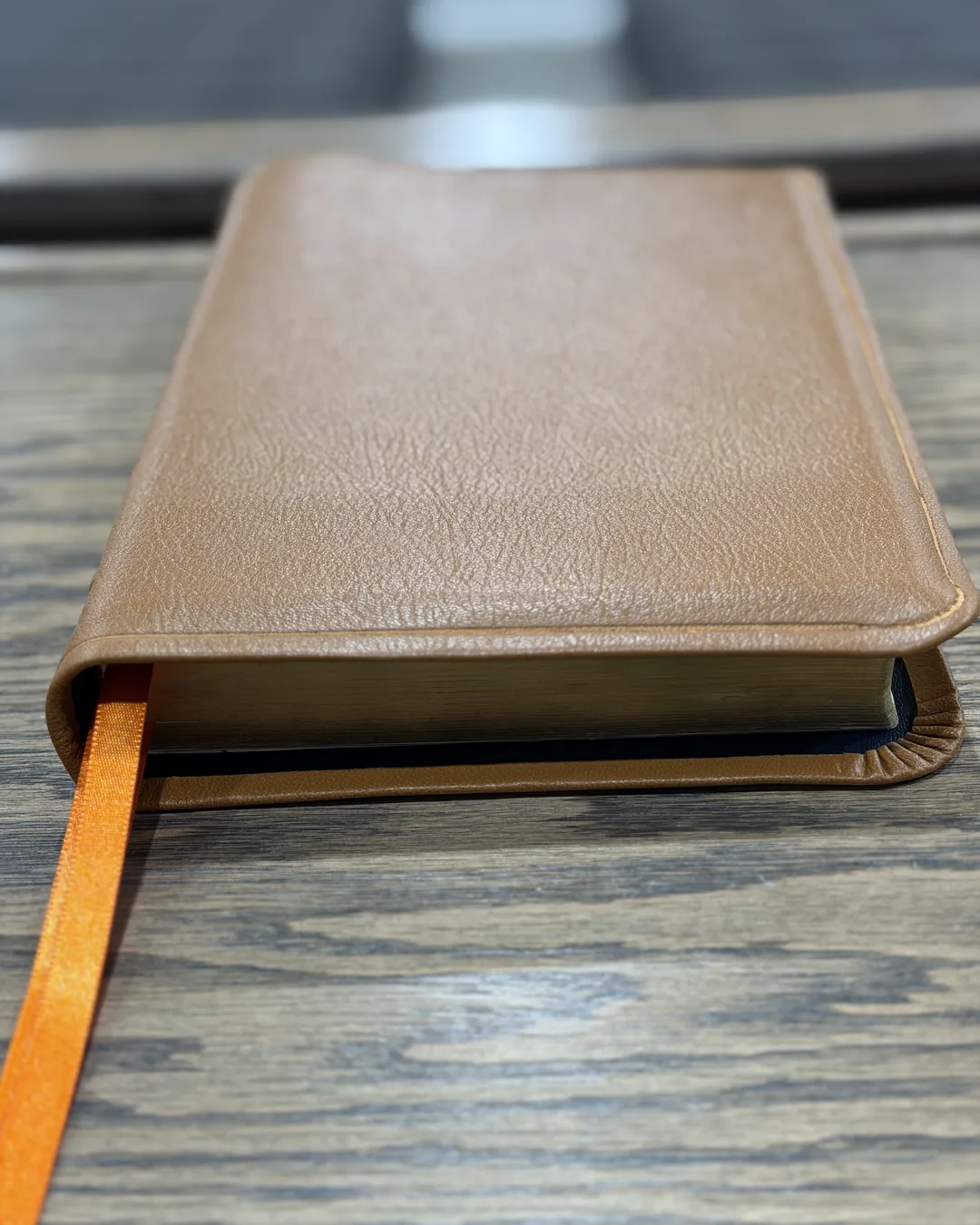 Tan leather Bible with orange ribbon, close view